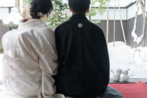 縁側で雪だるまをつくり寄り添う新郎新婦