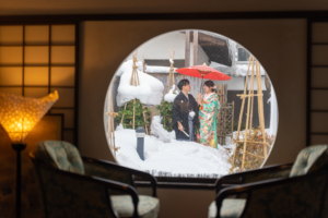 こんこんと雪が降る中 和傘を差してたたずむ新郎新婦