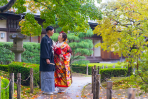 鮮やかな赤の色打掛の新婦と顔を見合わせてほほ笑む新郎