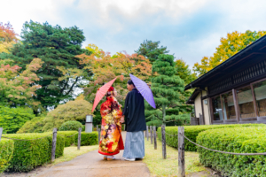 和傘を持ち笑顔で見つめあう新郎新婦