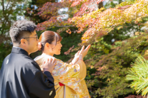 紅葉の葉を手に取り秋の始まりを感じる新郎新婦
