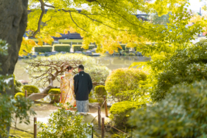 柔らかい日差しが差し込む池の前に立つ新郎新婦