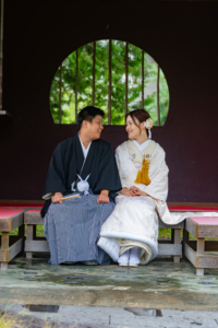 丸窓の前のベンチで微笑みあう新郎新婦